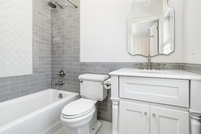 full bathroom featuring vanity, toilet, tiled shower / bath combo, and tile walls