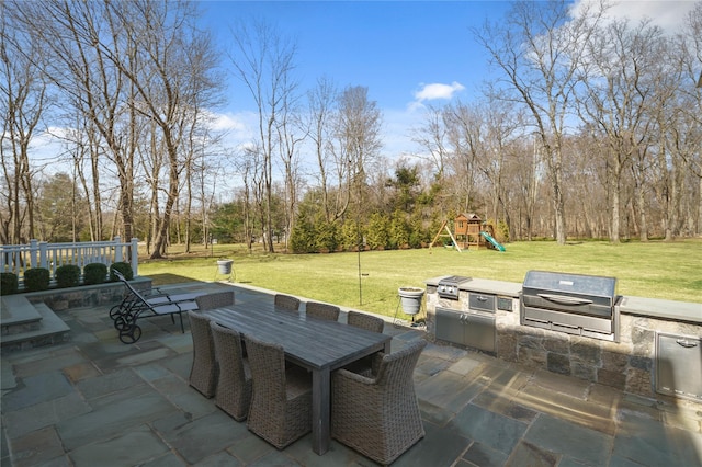 view of patio with grilling area, a playground, and exterior kitchen