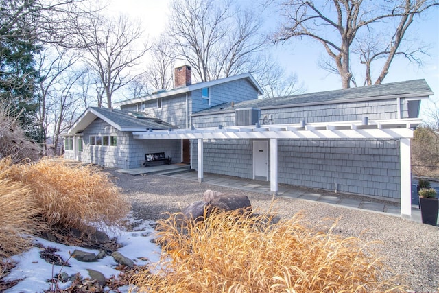 view of side of property with a shingled roof and a chimney