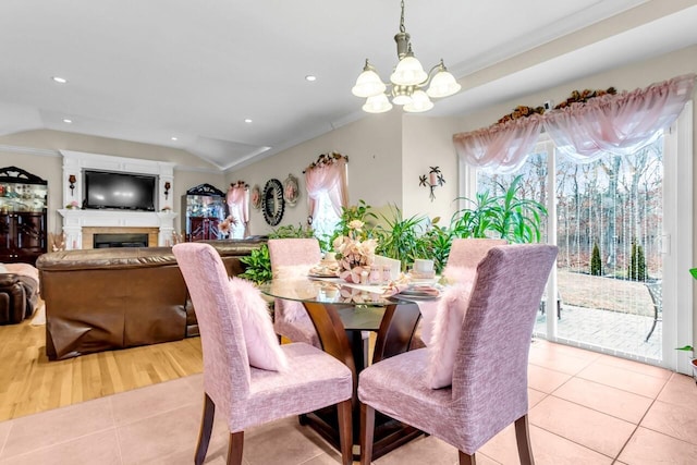 dining area with ornamental molding, lofted ceiling, light tile patterned floors, and an inviting chandelier