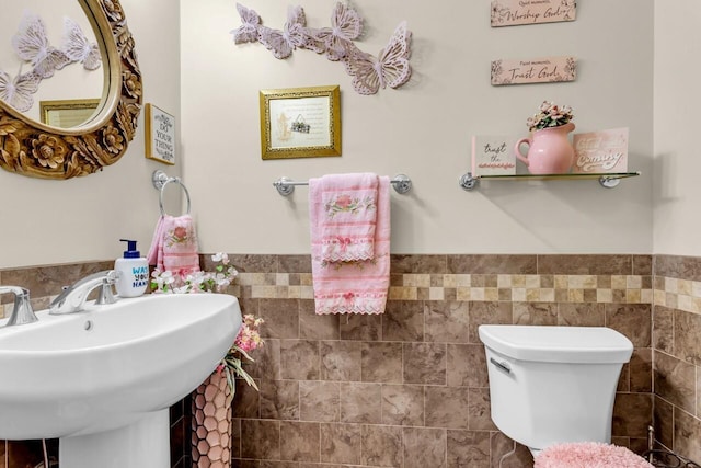 bathroom featuring sink, tile walls, and toilet