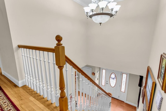 stairs with an inviting chandelier, a towering ceiling, and crown molding