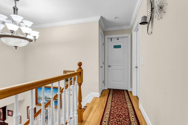 hall with ornamental molding, a notable chandelier, and light hardwood / wood-style flooring