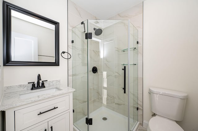 bathroom with vanity, a shower with shower door, and toilet