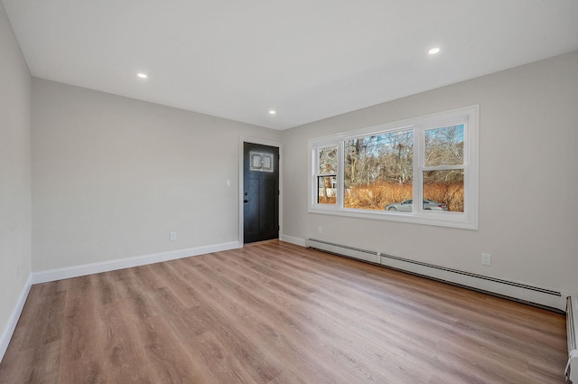 empty room featuring baseboard heating and light hardwood / wood-style floors