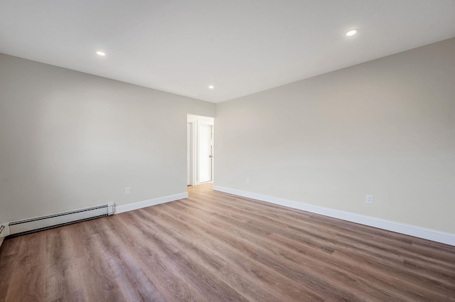 unfurnished room with baseboard heating and light hardwood / wood-style flooring