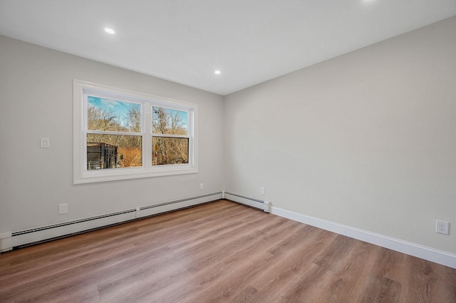 spare room featuring baseboard heating and light hardwood / wood-style floors