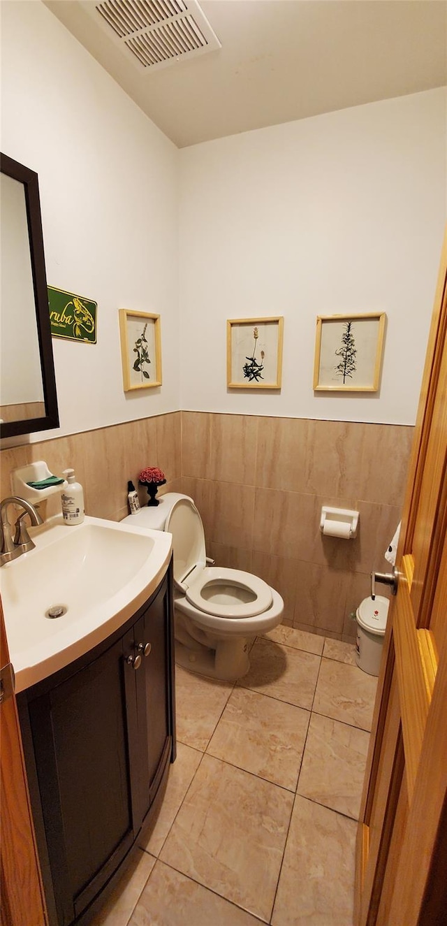 bathroom featuring vanity, tile patterned floors, tile walls, and toilet