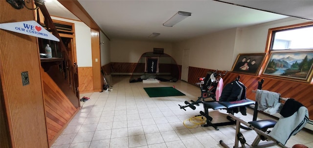 exercise room featuring light tile patterned flooring and wood walls