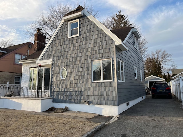 view of side of property featuring crawl space, a detached garage, fence, and a porch