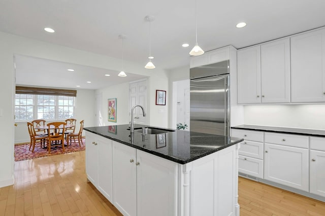 kitchen featuring white cabinets, a sink, light wood-style flooring, and built in refrigerator