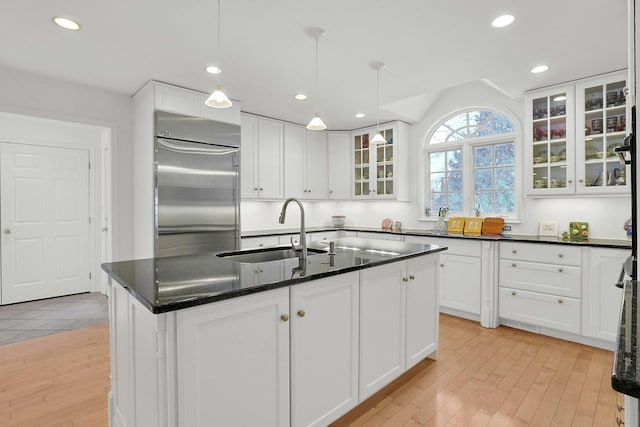 kitchen featuring stainless steel built in fridge, light wood-style floors, white cabinets, and a sink