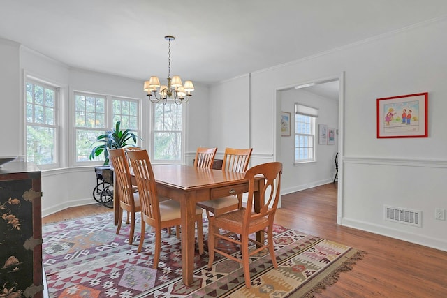 dining room featuring a chandelier, a healthy amount of sunlight, visible vents, and wood finished floors