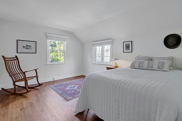 bedroom with lofted ceiling, baseboards, multiple windows, and hardwood / wood-style floors