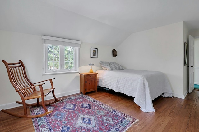 bedroom featuring lofted ceiling, baseboards, and wood finished floors