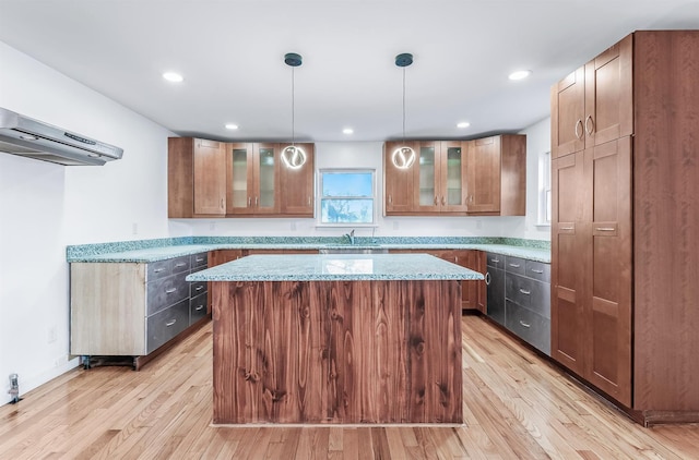 kitchen featuring light stone countertops, a kitchen island, sink, and decorative light fixtures