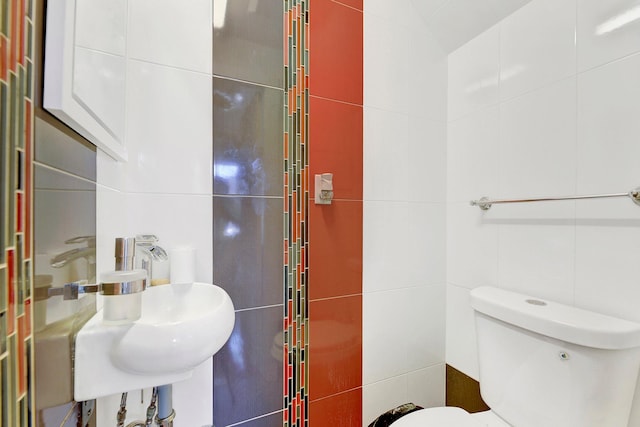 bathroom featuring toilet, sink, and tile walls