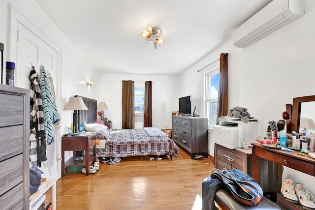 bedroom with a wall unit AC and light hardwood / wood-style flooring