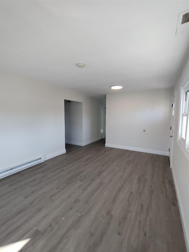 empty room featuring dark hardwood / wood-style flooring and a baseboard heating unit