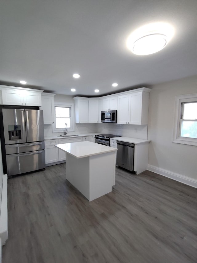 kitchen with sink, appliances with stainless steel finishes, dark hardwood / wood-style floors, a kitchen island, and white cabinets