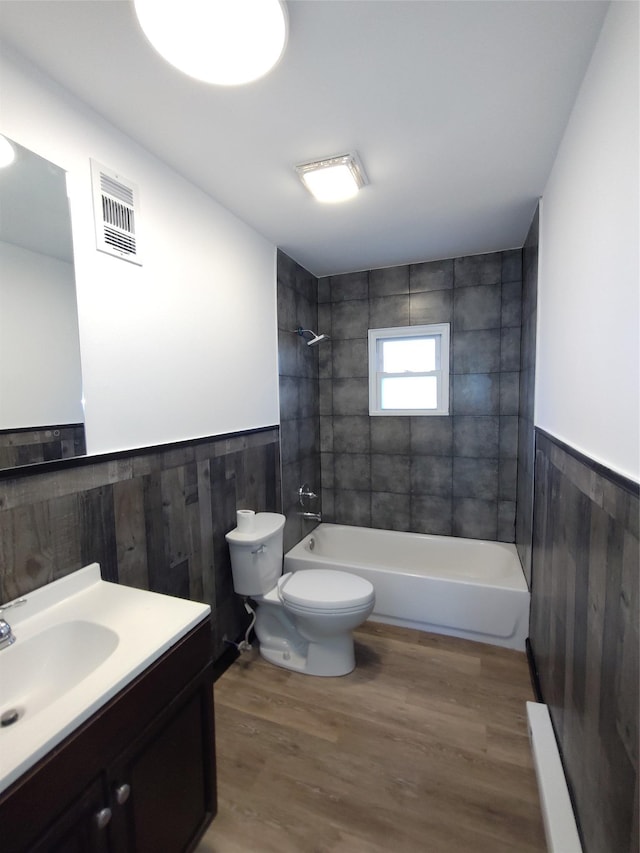 full bathroom with vanity, tiled shower / bath combo, toilet, and hardwood / wood-style flooring