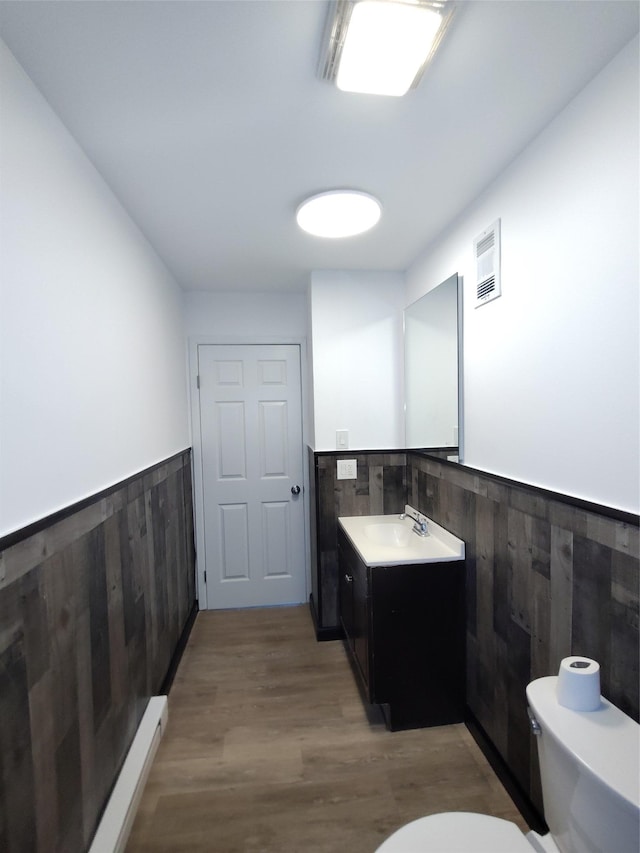 bathroom with vanity, hardwood / wood-style flooring, wooden walls, and toilet