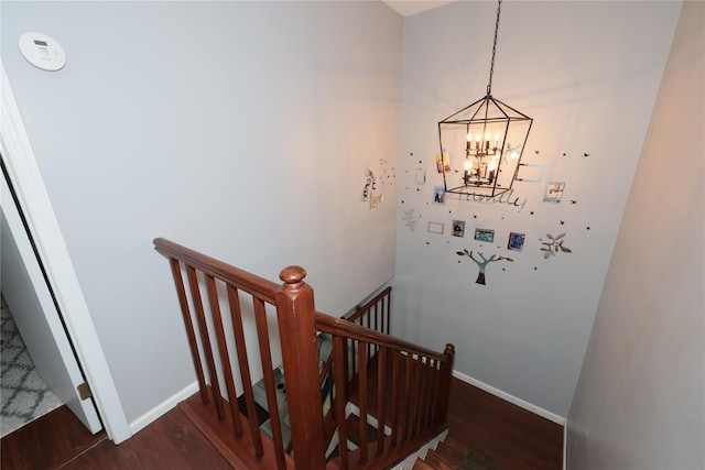 staircase featuring wood-type flooring and a notable chandelier