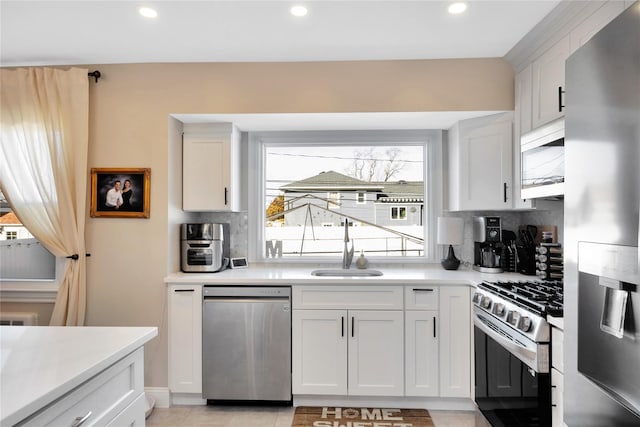 kitchen with white cabinetry, stainless steel appliances, sink, and tasteful backsplash