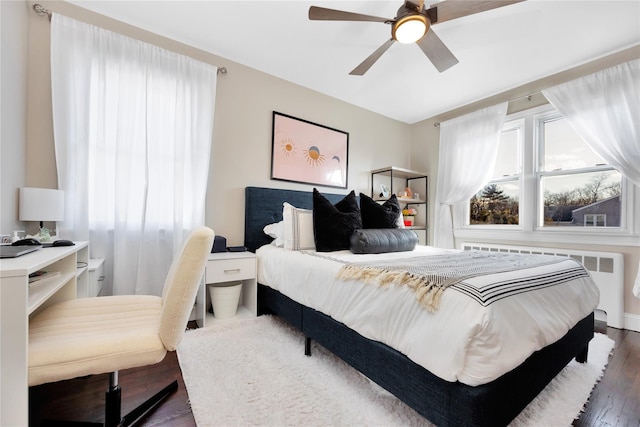 bedroom featuring multiple windows, radiator, and dark hardwood / wood-style floors