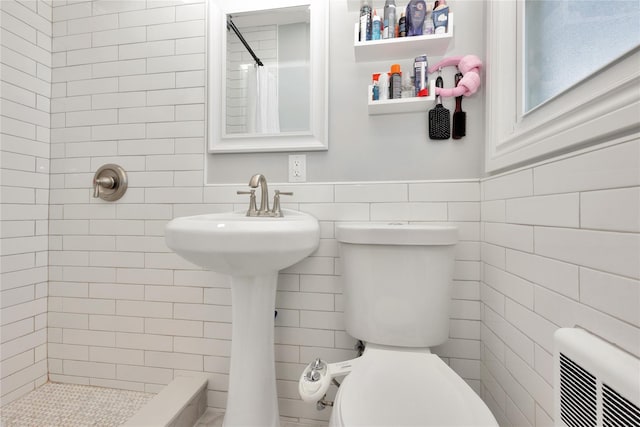 bathroom with tile walls, curtained shower, and toilet