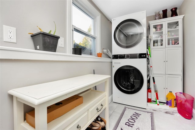 clothes washing area featuring cabinets and stacked washer / dryer