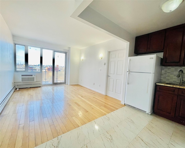 kitchen with sink, backsplash, a wall unit AC, white refrigerator, and light hardwood / wood-style floors