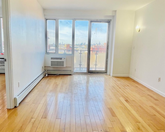 empty room featuring a baseboard radiator, a wall mounted AC, and light hardwood / wood-style floors