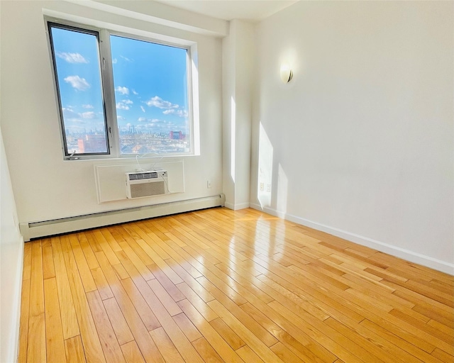 empty room with light wood-type flooring, a wall unit AC, and a baseboard heating unit