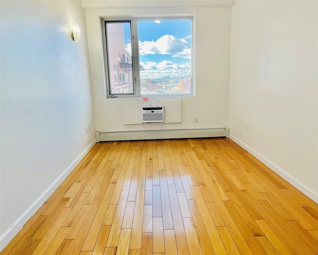 unfurnished room featuring a baseboard heating unit, a wall mounted AC, and light hardwood / wood-style floors