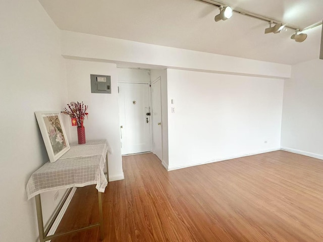 interior space with wood-type flooring, track lighting, and electric panel