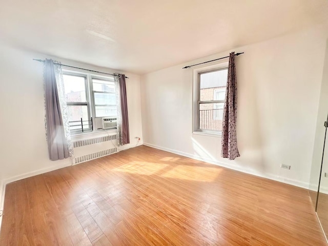 spare room with cooling unit, radiator, and light hardwood / wood-style floors