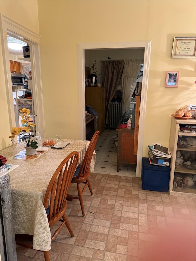 dining area with radiator heating unit and brick patterned floor