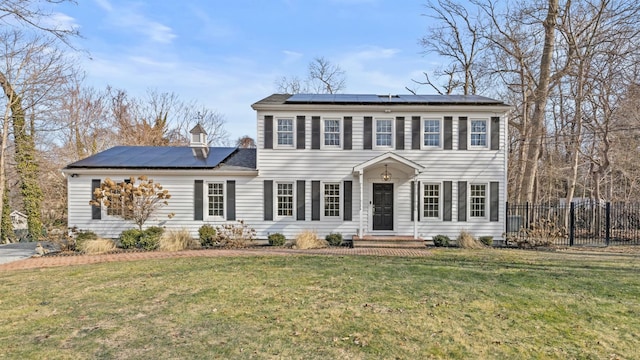 colonial home with a front lawn and solar panels