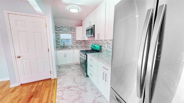 kitchen featuring white cabinetry, appliances with stainless steel finishes, sink, and decorative backsplash