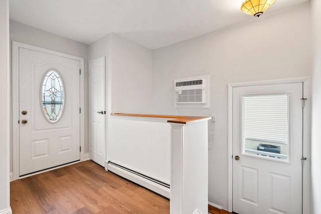 entryway featuring hardwood / wood-style flooring, a wealth of natural light, a wall unit AC, and a baseboard heating unit