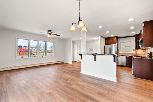 kitchen with a baseboard radiator, appliances with stainless steel finishes, light hardwood / wood-style floors, and a kitchen island