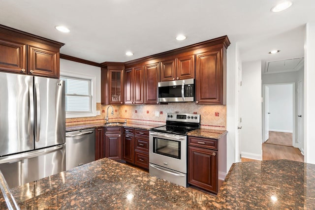 kitchen with sink, crown molding, dark stone countertops, backsplash, and stainless steel appliances