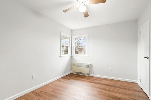 empty room featuring hardwood / wood-style floors, radiator heating unit, and ceiling fan