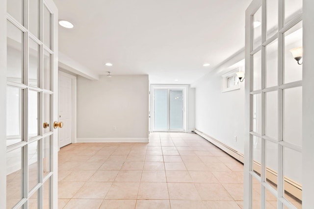 empty room featuring light tile patterned flooring, a baseboard heating unit, and french doors