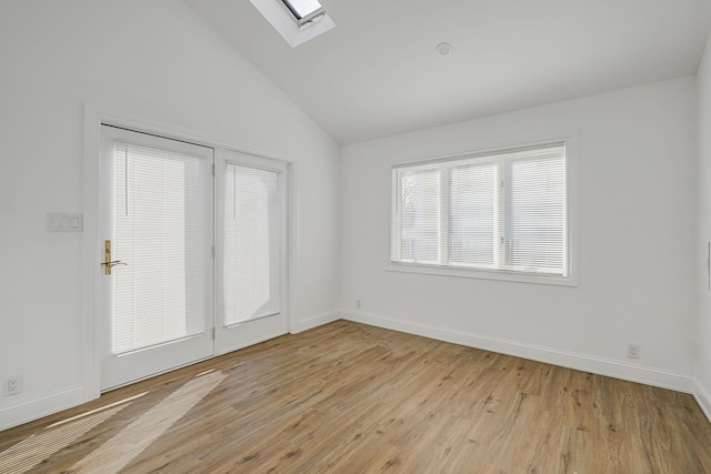 interior space with vaulted ceiling with skylight and light hardwood / wood-style floors