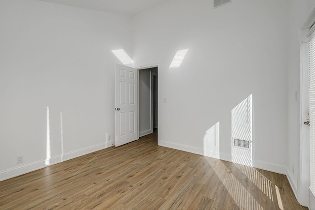 empty room featuring a high ceiling and light wood-type flooring