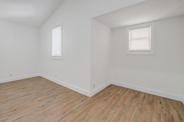 spare room featuring vaulted ceiling, light wood-type flooring, and a wealth of natural light