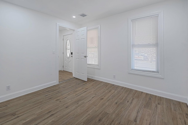 empty room featuring a healthy amount of sunlight and dark hardwood / wood-style flooring