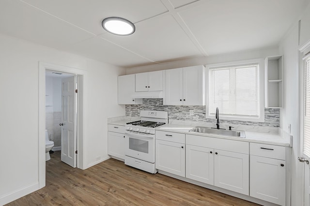 kitchen with light wood-type flooring, white gas range, sink, and white cabinets